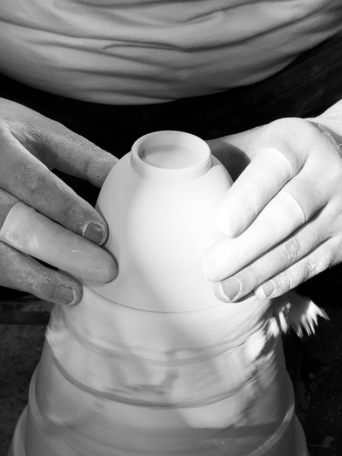 Hands shaping a handmade ceramic vessel in the studio